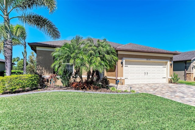 view of front of home featuring a garage, decorative driveway, a front yard, and stucco siding