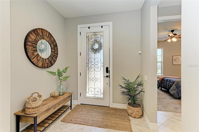 entryway featuring light tile patterned flooring, ceiling fan, and baseboards