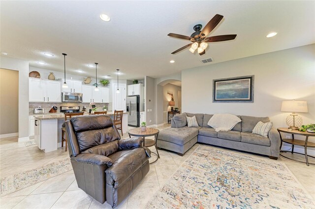 living area with light tile patterned floors, ceiling fan, arched walkways, and recessed lighting