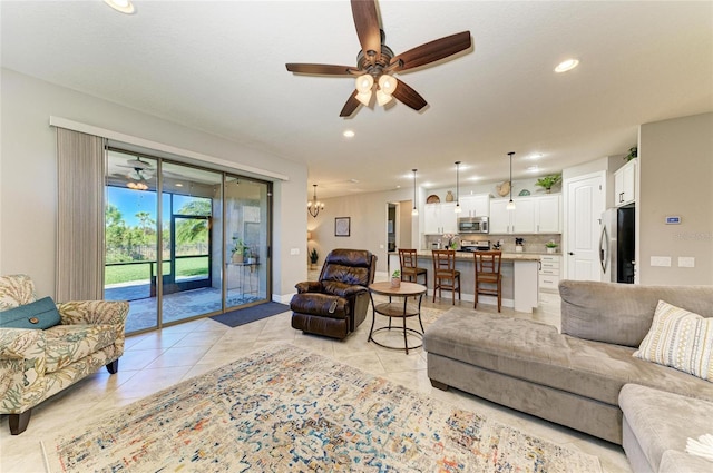 living area featuring ceiling fan with notable chandelier, light tile patterned flooring, baseboards, and recessed lighting