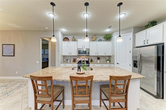 kitchen with stainless steel appliances, a sink, visible vents, white cabinets, and backsplash