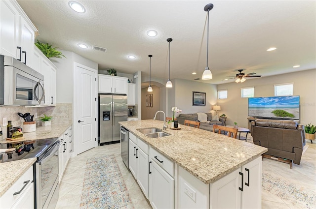 kitchen featuring white cabinets, appliances with stainless steel finishes, open floor plan, and a sink