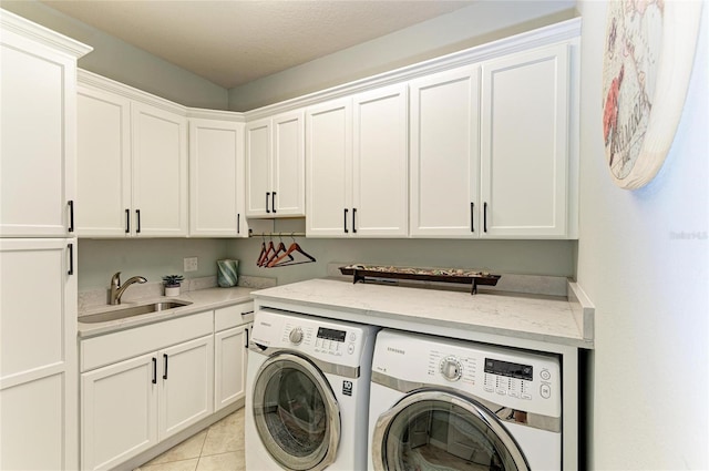 laundry room featuring cabinet space, light tile patterned floors, washer and clothes dryer, and a sink