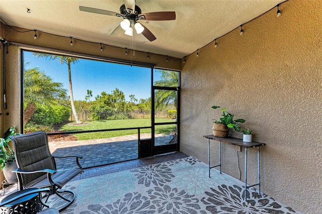 unfurnished sunroom with ceiling fan