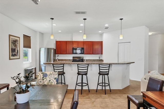 kitchen featuring pendant lighting, a kitchen bar, visible vents, and appliances with stainless steel finishes