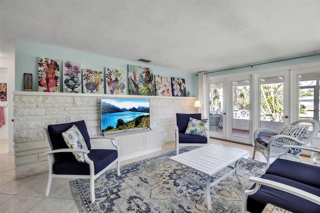 tiled living room with a textured ceiling, visible vents, and a wealth of natural light