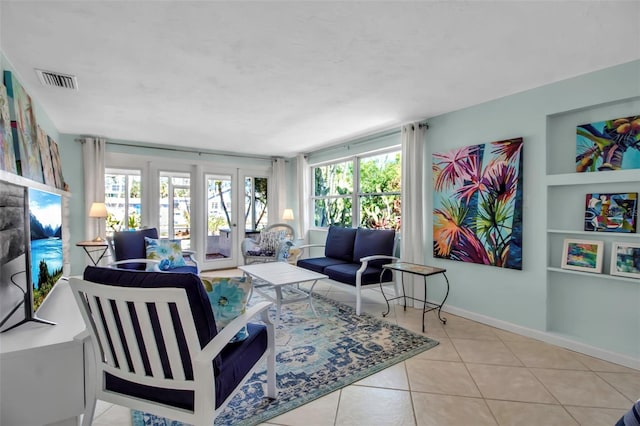 tiled living room with built in features, french doors, visible vents, and baseboards