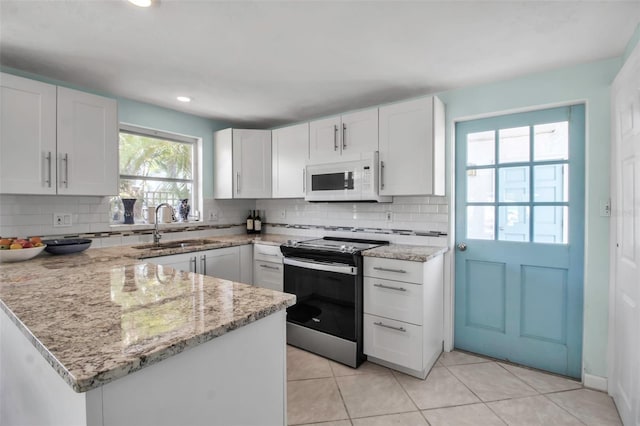 kitchen with white cabinets, electric stove, white microwave, a peninsula, and a sink