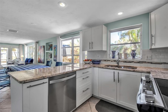 kitchen featuring light tile patterned floors, electric range oven, a peninsula, stainless steel dishwasher, and a sink