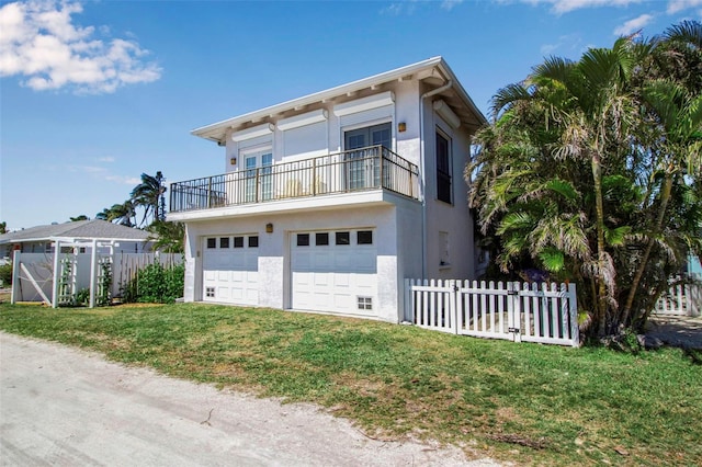 view of front facade with a garage, fence, a balcony, and stucco siding