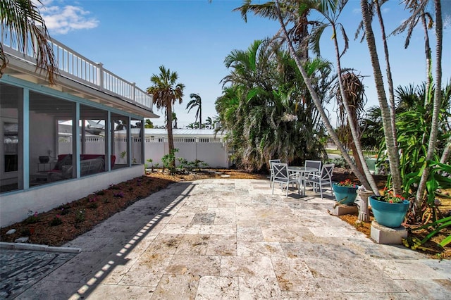 view of patio / terrace with a sunroom, fence, and outdoor dining space