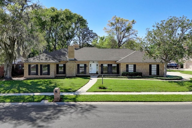 view of front of house with a front lawn, brick siding, and a chimney