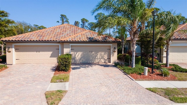 mediterranean / spanish-style home featuring stucco siding, a tile roof, and a garage