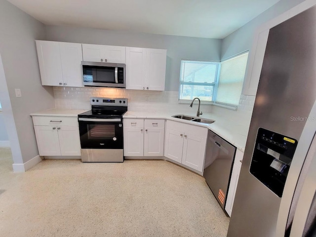 kitchen featuring decorative backsplash, appliances with stainless steel finishes, white cabinets, and a sink