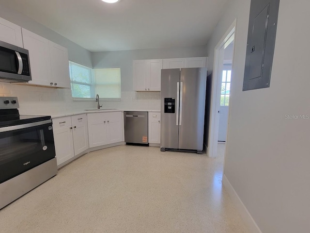 kitchen with backsplash, appliances with stainless steel finishes, white cabinets, a sink, and electric panel