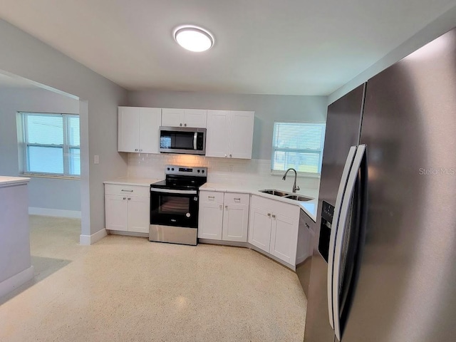 kitchen featuring stainless steel appliances, backsplash, a sink, and white cabinets