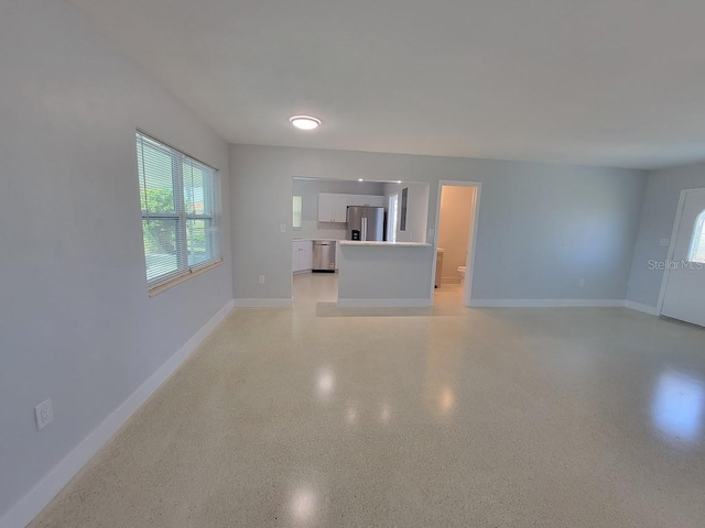 unfurnished living room with light speckled floor and baseboards