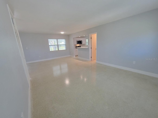 unfurnished living room with baseboards and light speckled floor