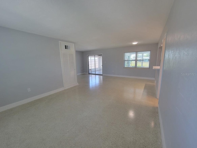 empty room featuring light speckled floor and baseboards