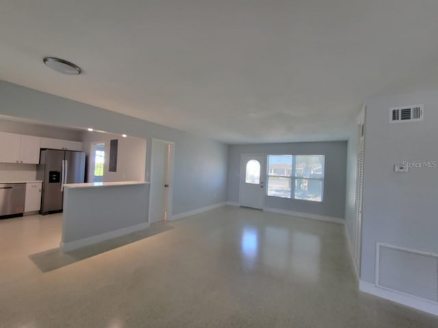 unfurnished living room featuring visible vents and baseboards