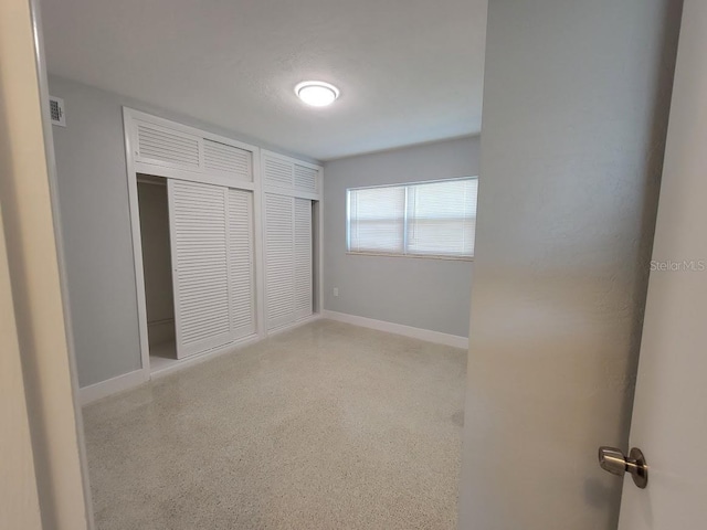 unfurnished bedroom featuring visible vents, baseboards, and speckled floor