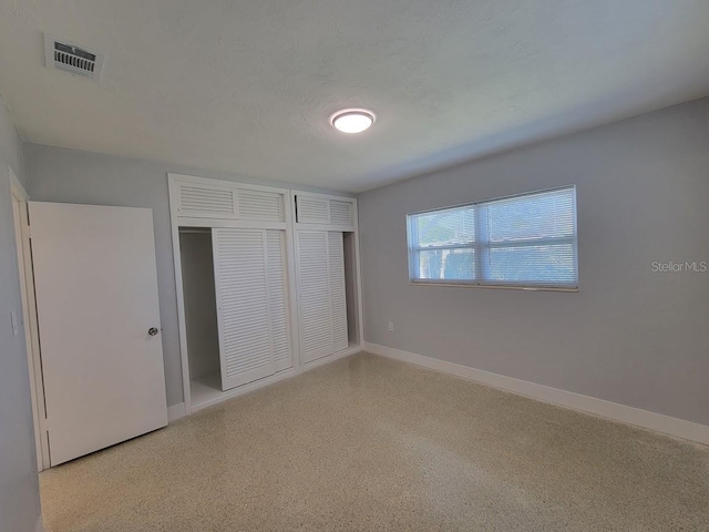 unfurnished bedroom featuring visible vents, baseboards, a textured ceiling, and speckled floor