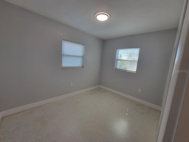 empty room featuring speckled floor and baseboards