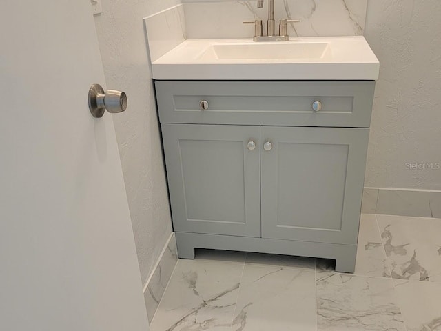 bathroom with marble finish floor, a textured wall, and vanity