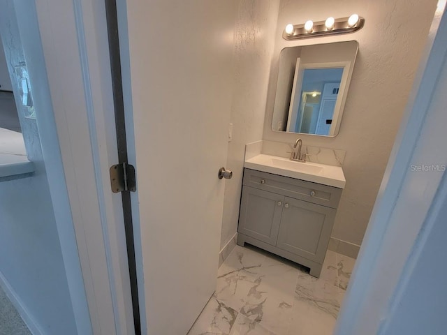 bathroom with marble finish floor, vanity, and baseboards