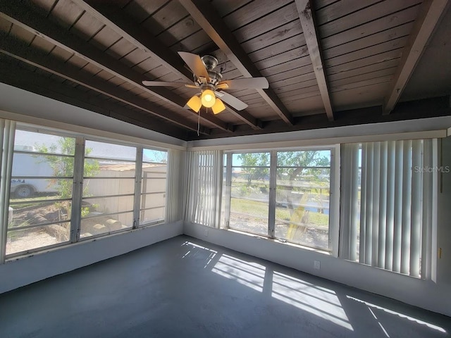 unfurnished sunroom featuring ceiling fan, beamed ceiling, wooden ceiling, and a wealth of natural light