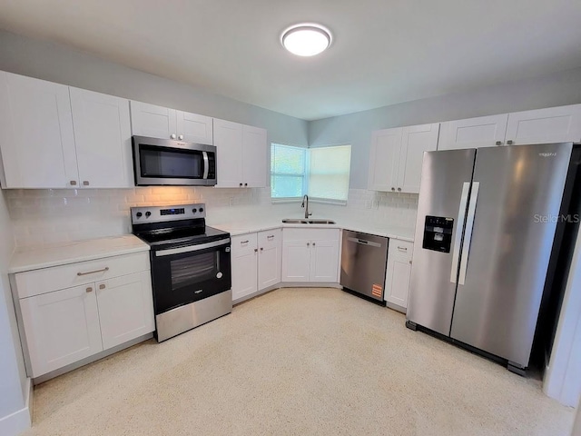 kitchen with a sink, stainless steel appliances, tasteful backsplash, and light countertops