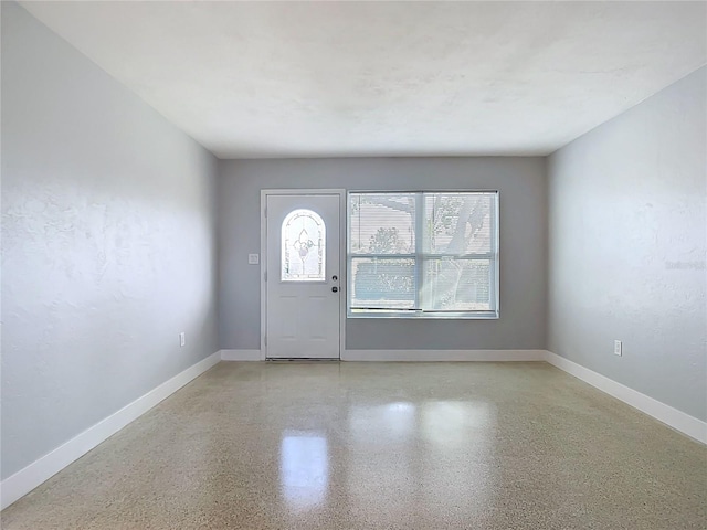 foyer featuring speckled floor and baseboards