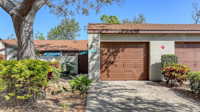 garage with concrete driveway and fence