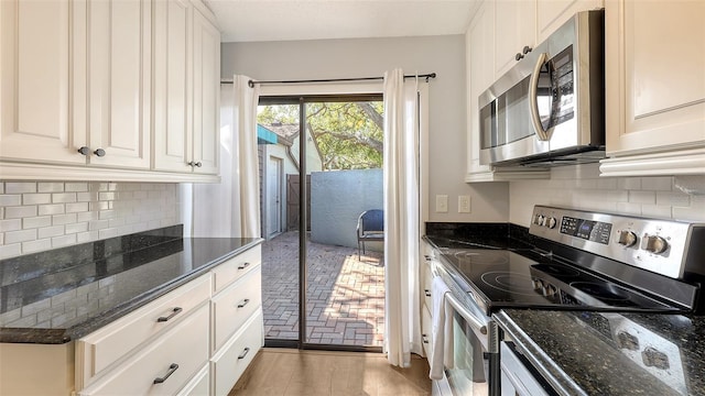 kitchen with tasteful backsplash, appliances with stainless steel finishes, and dark stone counters