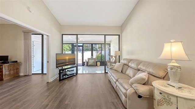 living room featuring baseboards, a ceiling fan, lofted ceiling, and wood finished floors