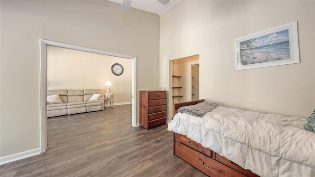 bedroom featuring dark wood-style floors, baseboards, and a towering ceiling