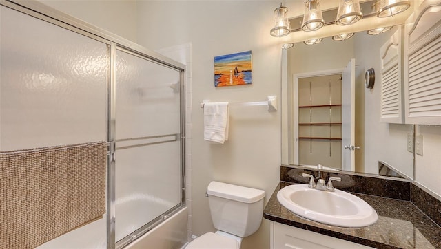 bathroom featuring enclosed tub / shower combo, toilet, and vanity