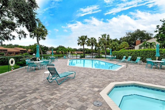 community pool with a patio area, a community hot tub, and fence