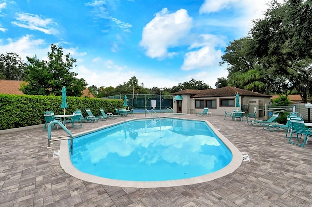 community pool with a patio and fence