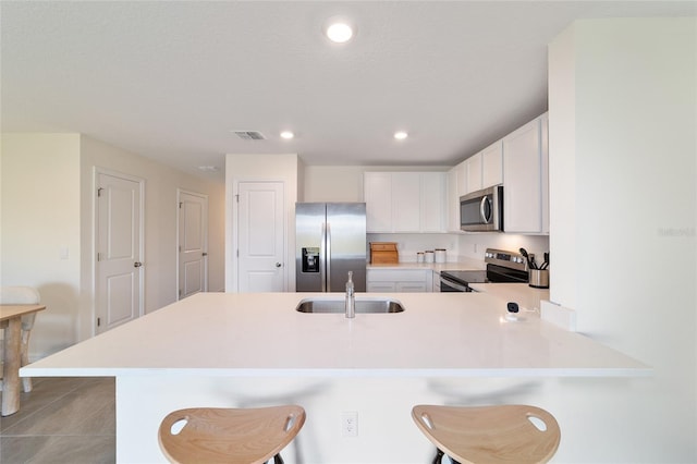 6677 SW 81st Loop, Ocala, FL 34476 - kitchen with a breakfast bar, light countertops, a peninsula, white cabinets, and stainless steel appliances