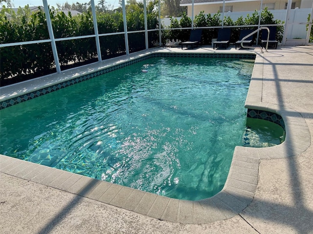 pool featuring a lanai, a patio area, and fence