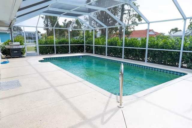 pool featuring glass enclosure, a patio area, and a grill