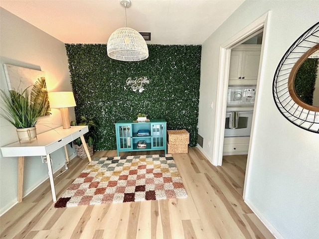 interior space with an accent wall, wood finished floors, baseboards, stairs, and wallpapered walls