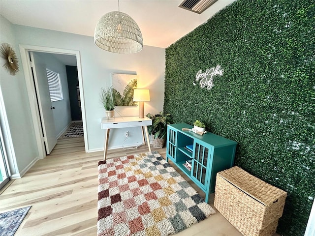 interior space with an accent wall, wood finished floors, visible vents, and baseboards