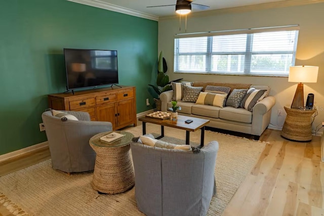 living room featuring ornamental molding, light wood-style flooring, baseboards, and a ceiling fan