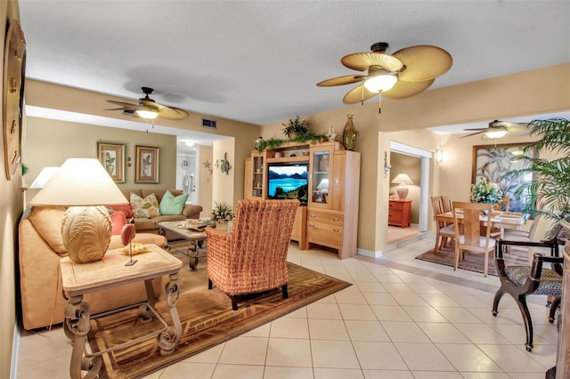 living room featuring light tile patterned floors, visible vents, and a ceiling fan