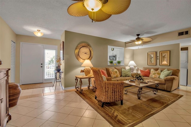 living area with light tile patterned floors, visible vents, baseboards, a ceiling fan, and a textured ceiling