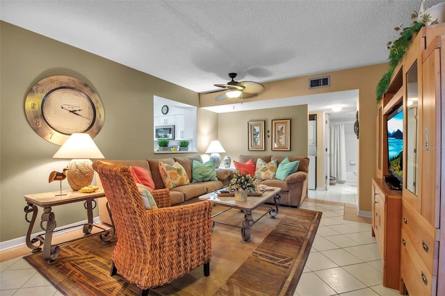 living area featuring visible vents, light tile patterned flooring, ceiling fan, a textured ceiling, and baseboards