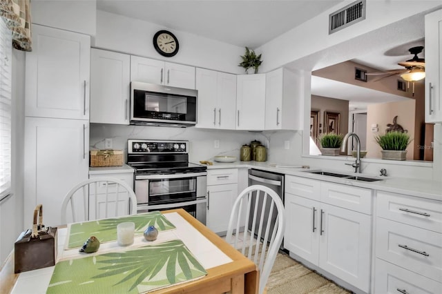 kitchen featuring stainless steel appliances, light countertops, a sink, and visible vents