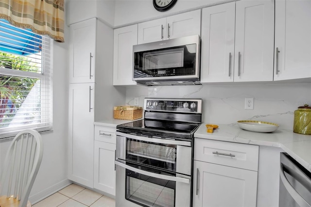 kitchen with light tile patterned floors, tasteful backsplash, white cabinetry, and stainless steel appliances